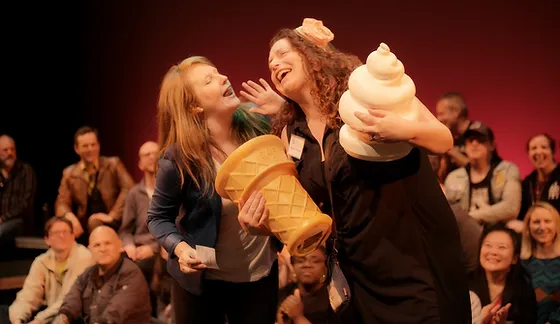 Two women singing to each other holding a large ice cream cone