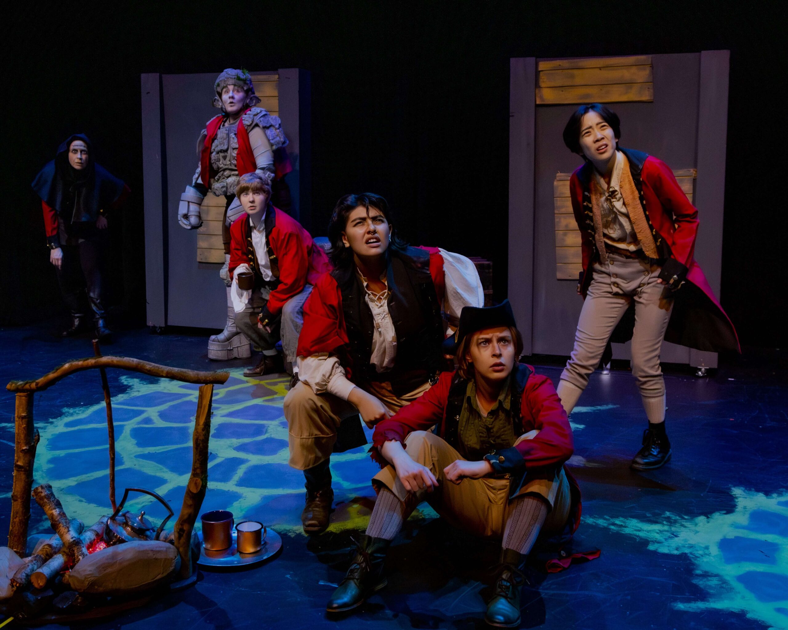 6 actors in regiment red coats on a dark stage